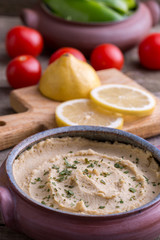 Humus in homemade bowl with vegetable around.