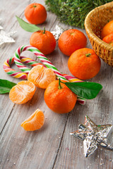 Fresh Tangerines with leaves and Christmas decor with Xmas tree and candies on white old wooden table. Rustic style. Selective focus. Winter holiday concept
