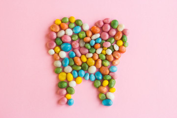 Tooth of sweets scattered on a pink background