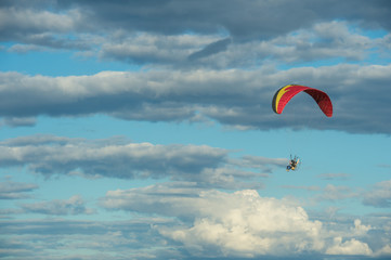 Paramotor flying over the fields in the sky.