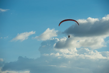 Paramotor flying over the fields in the sky.