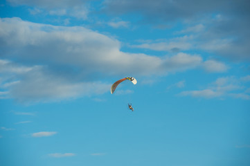 Paramotor flying over the fields in the sky.