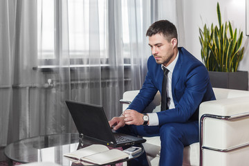 Young businessman working at laptop in lobby