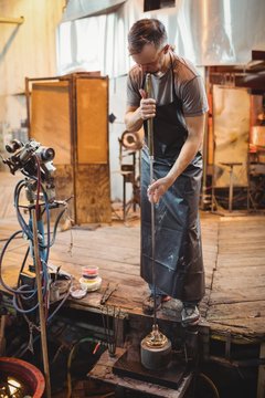 Glassblower using mold to shape a molten glass