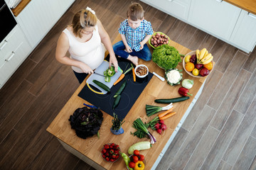 Pregnant woman preparing meal with son