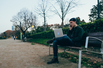 A man talking on the phone while working on his laptop