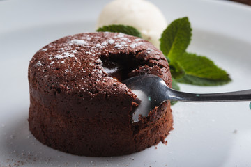 Concept: restaurant menus, healthy eating, homemade, gourmands, gluttony. White plate with chocolate fondant and ice cream on a messy vintage wooden background.