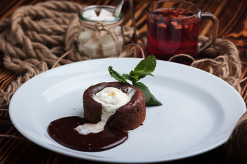 Concept: restaurant menus, healthy eating, homemade, gourmands, gluttony. White plate with chocolate fondant and ice cream on a messy vintage wooden background.