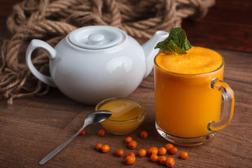 Concept: restaurant menus, healthy eating, homemade, gourmands, gluttony. Buckthorn juice in a glass with honey and ingredients on vintage weathered wooden background.