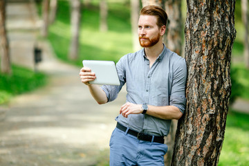 Businessman using tablet pc in nature