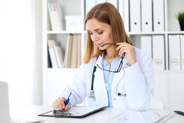 Female doctor  writing a medical prescription at clipboard