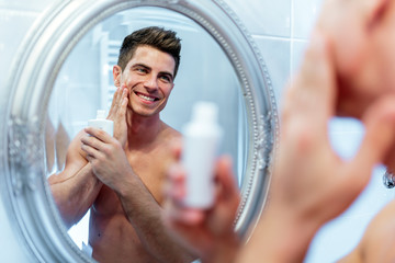 Healthy positive male treating sking with lotion