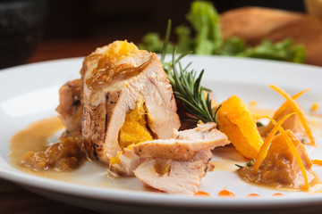 Concept: restaurant menus, healthy eating, homemade, gourmands, gluttony. White plate of chicken breast stuffed with orange brazilian way on vintage weathered wooden table.