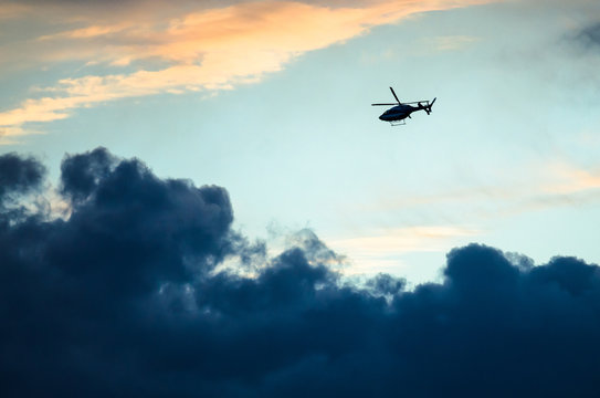 Silhouetted Helicopter Flying Across a Sunset Sky