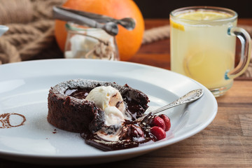Concept: restaurant menus, healthy eating, homemade, gourmands, gluttony. White plate with chocolate fondant with strawberry and ice cream on a messy vintage wooden background.
