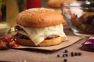 Concept: restaurant menus, healthy eating, homemade, gourmands, gluttony. Classic double cheeseburger with ingredients, drinks and potato wedges on messy vintage wooden background.