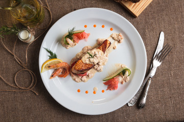 Concept: restaurant menus, healthy eating, homemade, gourmands, gluttony. Grilled salmon with shrimp and cream sauce with ingredients and vintage cutlery on sackcloth background. Top-down view.