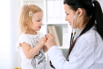 Pediatrician is taking care of baby in hospital. Little girl is being examine by doctor with stethoscope. Health care, insurance and help concept.