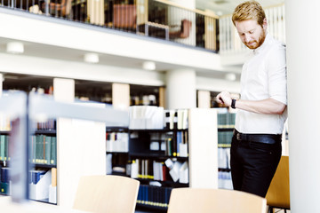 Handsome student checking time in library