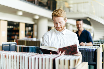 Obraz premium Handsome student reading a book in a library