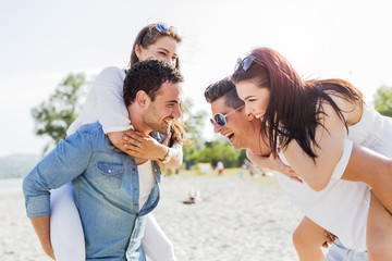 Group of young happy people carrying women on a sandy beach
