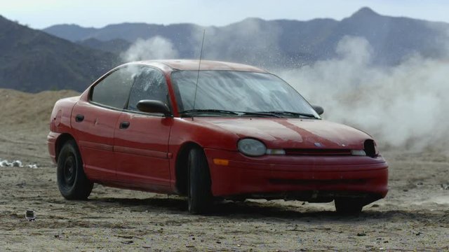 A tight shot of a red car shot up by bullets in slow motion.