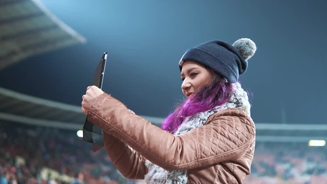 A fan woman taking pictures of a stadium