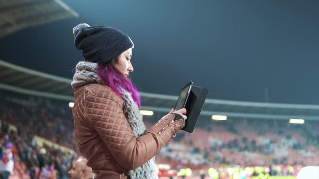 A fan girl taking pictures of a football game