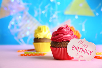 Delicious cupcake and greeting card on table. Text HAPPY BIRTHDAY TO YOU on card.
