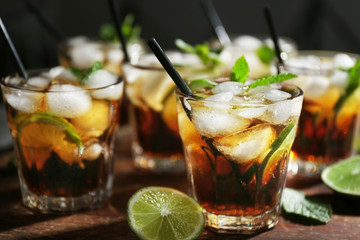 Glasses of cocktail with ice on wooden cutting board closeup