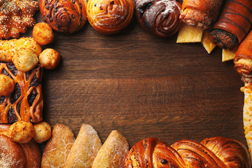 Frame of assorted fresh pastries on wooden background