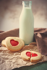 Cookies with milk and parchment on table, closeup
