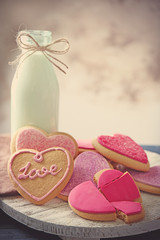 Heart shaped cookies with milk on wooden table, closeup