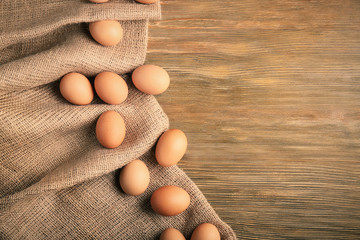 Raw eggs on sackcloth on wooden table