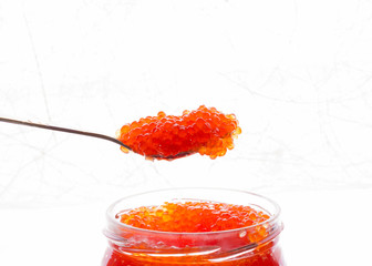 Spoon of red caviar for breakfast. Spoon the red, delicious, juicy roe over the bank. Behind textured white background