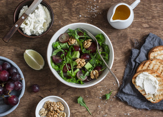Avocados, grapes and arugula salad. On a wooden table, top view