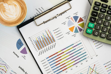 office desk working table with calculator, business graph or analysis chart and calculator cup of coffee.Top view with copy space.Office supplies and gadgets concept.