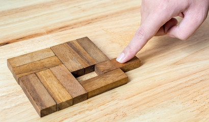 Hand push last piece of wood block to complete the unity, metaphor to key to success.