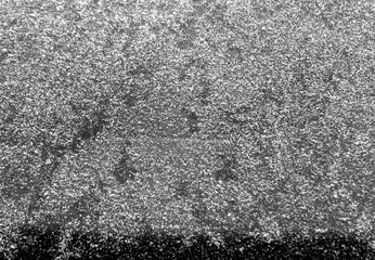 Grey snow and frost on car glass with blur effect.