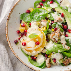 Salad with chicken, orange, spinach and pomegranate seeds.