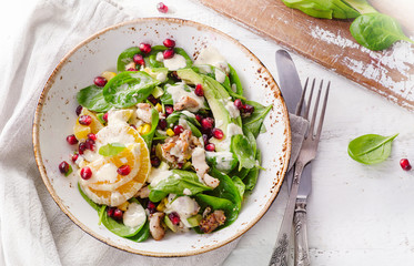 Salad with chicken, orange, spinach and pomegranate seeds.