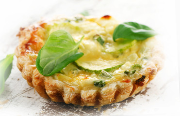 Tart with cheese on a white wooden table.