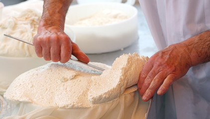 with a sharp knife a skilled cheesemaker cuts the cheese