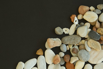 Different colors pebble stones on the black background © Svetlana