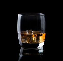 glass of whiskey and ice over a black background