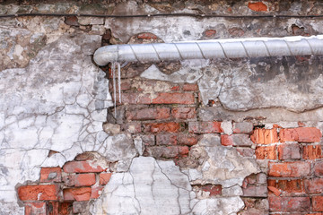 old brick wall of house with flowing pipe