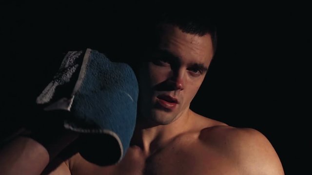 Strong toned young athlete towelling off in a gym wiping away sweat after doing a strenuous workout showing off his muscular physique, Slow motion