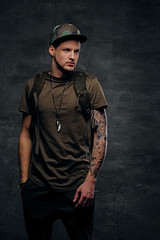 Urban style backpacker with tattooed arms, dressed in dark green