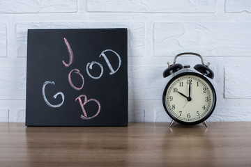 Retro alarm clock and text "good job" written with chalk on the blackboard.