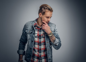 Positive blond bearded male dressed in a plaid shirt and denim j